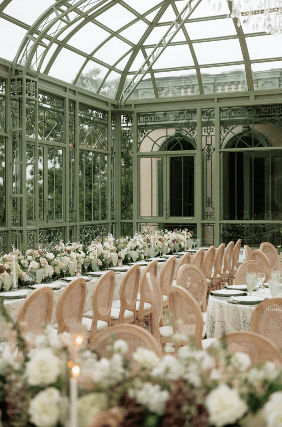 interior of glass house venue with wedding florals